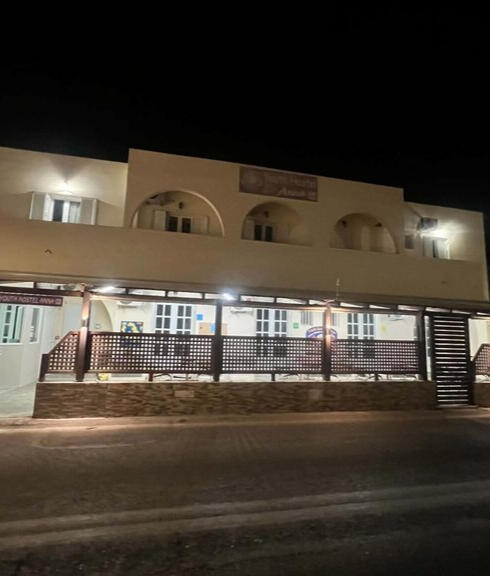 Wide night view of the illuminated Youth Hostel Anna building in Perissa.