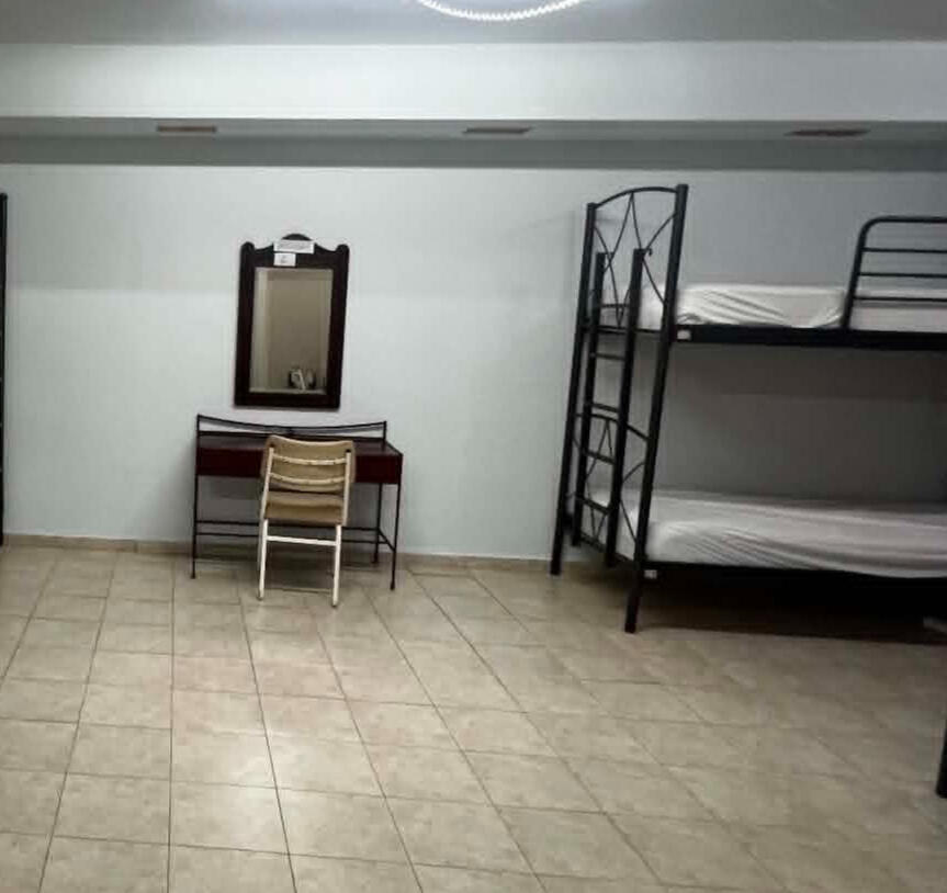 Air-conditioned shared dorm with pink bunk beds, lockers and natural light.