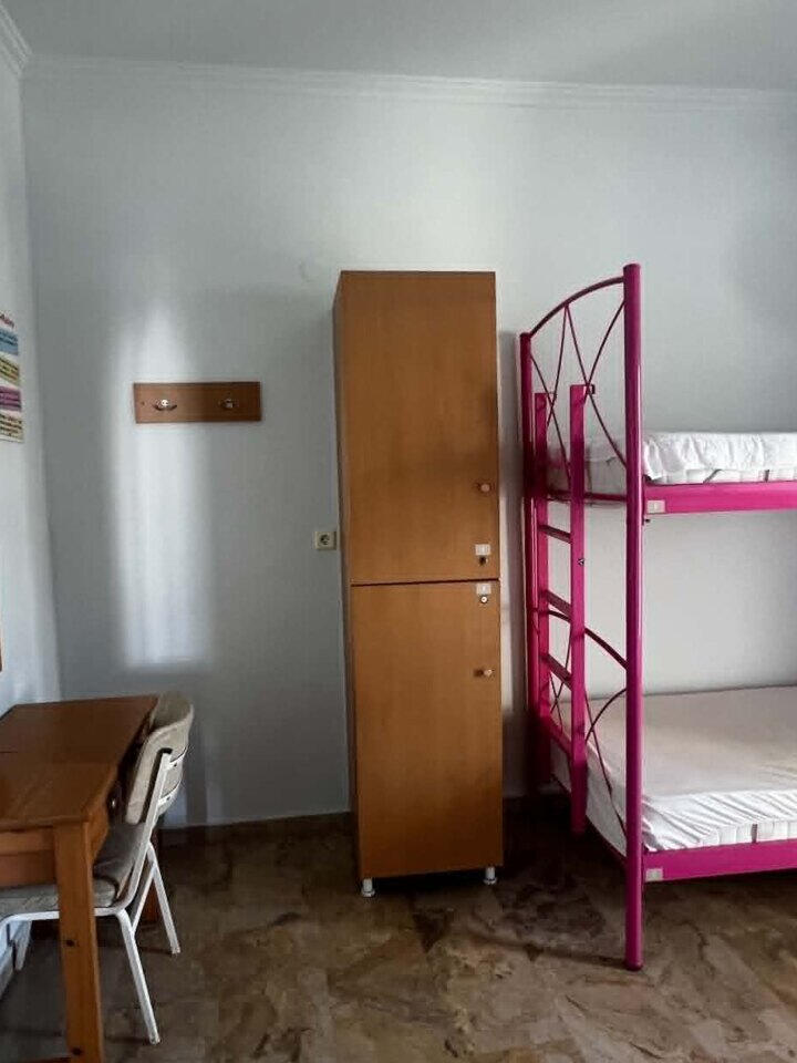 Bright dorm room with pink bunk beds, desk and guest lockers at Youth Hostel Anna